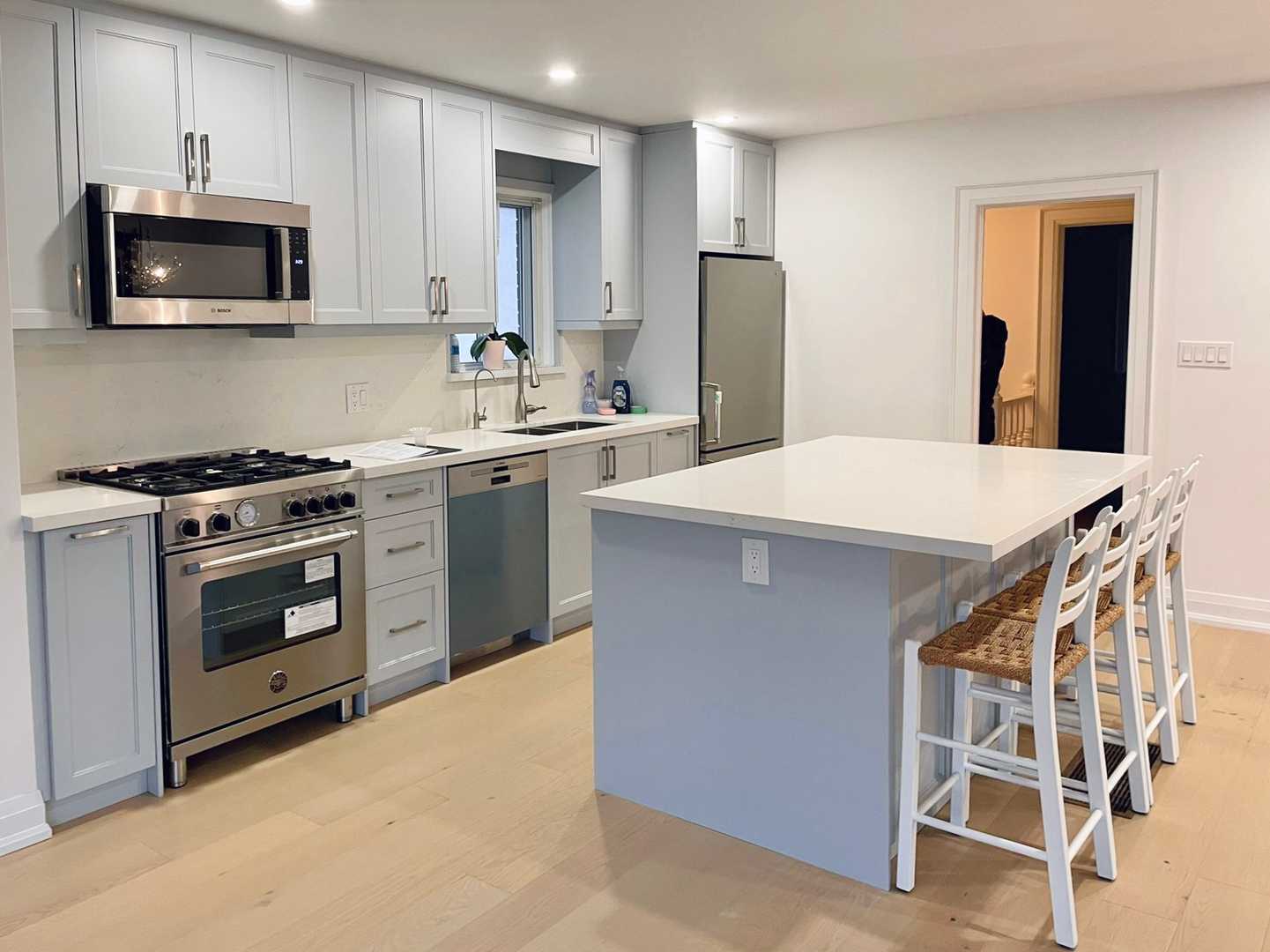 Light grey kitchen cabinets with chrome handles, white sintered stone