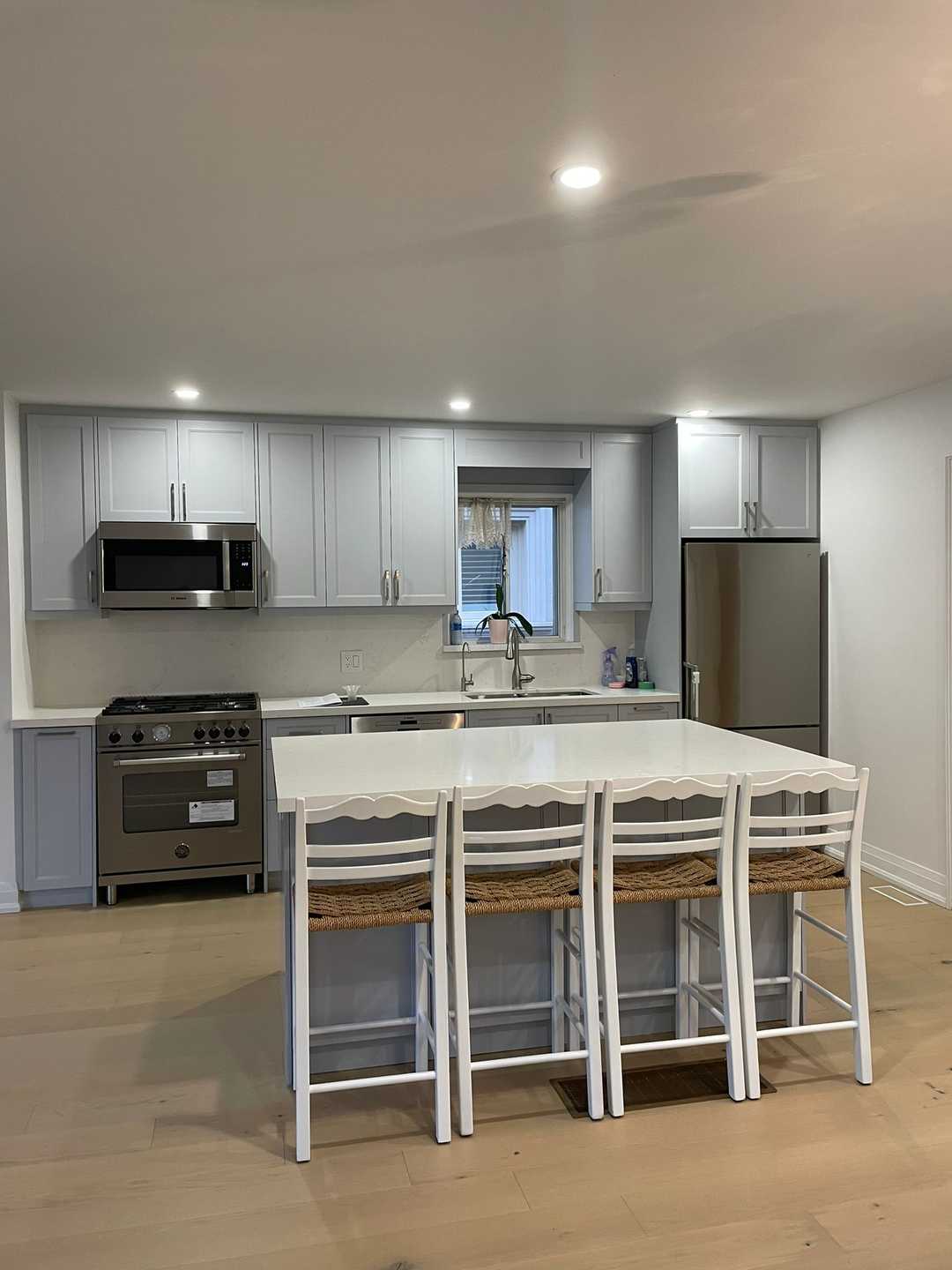 Light grey kitchen cabinets with chrome handles, white sintered stone